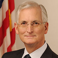 A man in suit and tie next to an american flag.